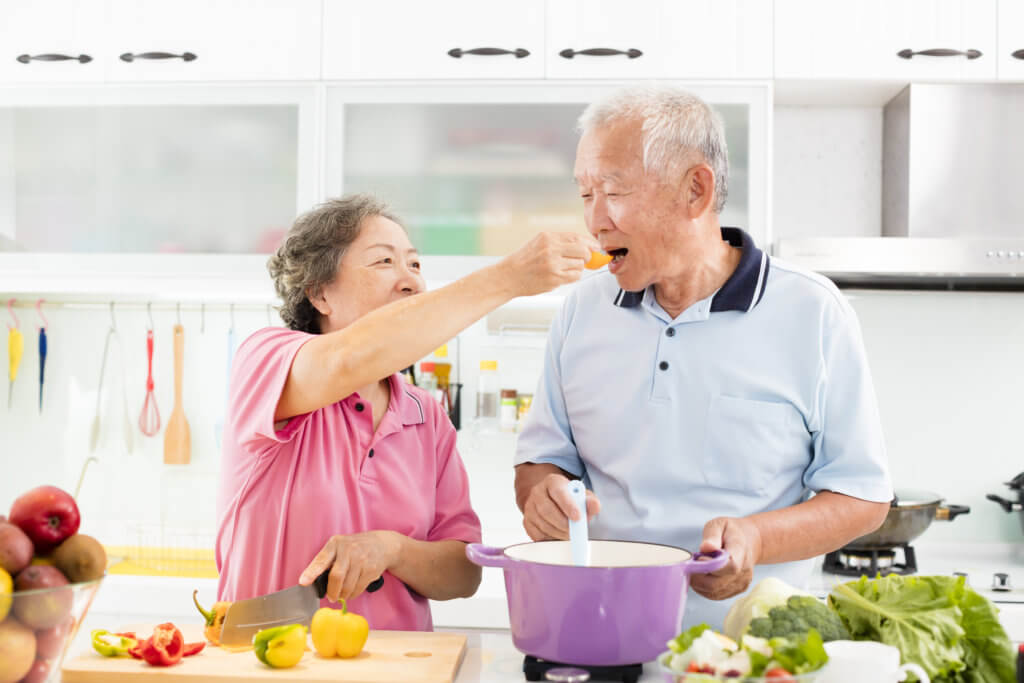 Happy senior couple cooking in kitchen, eating healthy
