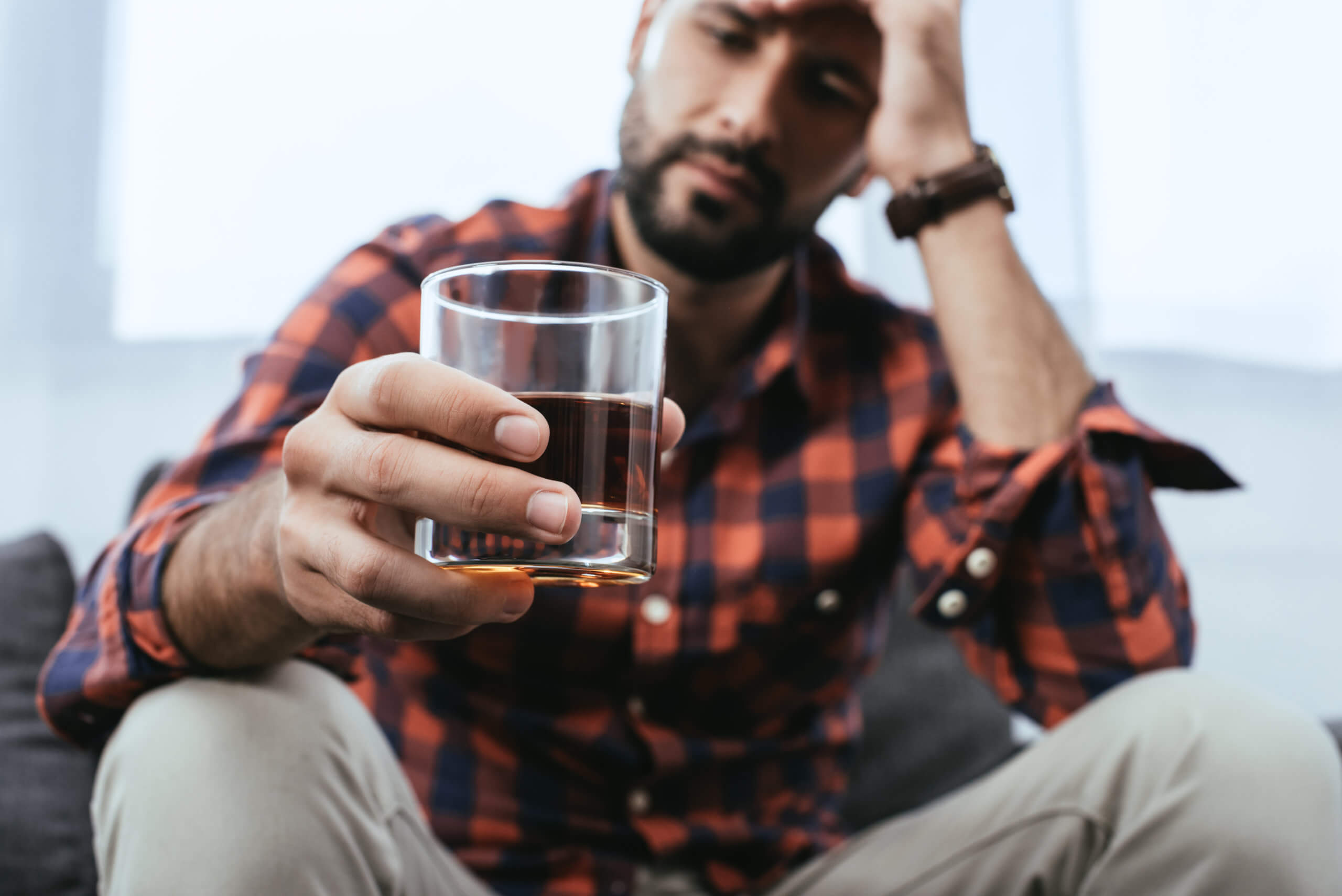 Man drinking glass of whiskey or alcohol, feeling stressed